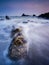 Vertical shot of rock formations in the foamy water of the sea