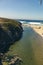 Vertical shot of a rocky cliff and a populated beach in sunny weather