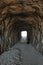 Vertical shot of a rocky tunnel going to a beach