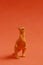 Vertical shot of a rubber dinosaur toy isolated on smooth red background