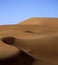 Vertical shot sandy hills in a desert with human traces and the sky in the background