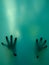 Vertical shot of scary hands of a woman from the back of a green glass portrait