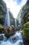 Vertical shot of scenic landscape of waterfalls falling into the riverbed in the middle of the paradisiacal tropical jungle