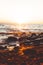 Vertical shot of a scenic sunset over the rocky shore and shining ocean