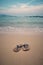 Vertical shot of the sea with a pair of slippers isolated on the beach