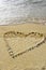 Vertical shot of seashells forming a heart shape on the beach surrounded by the sea