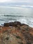 Vertical shot of the seawater splashing on the mossy rocks