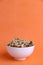 Vertical shot of shelled walnut bowl on orange background