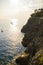Vertical shot of a shiny sea with boats and coastline cliffs with bushes at sunset in Monterosso