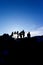 Vertical shot of silhouette of group of hikers walking through the rocky volcanic landscape in the Volcan Poas National Park in