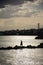 Vertical shot of a silhouette of a person fishing at the shore at bright sunrise