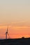 Vertical shot of a silhouette of a windmill on a grass field in a dramatic sunset sky