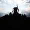 Vertical shot of silhouetted windmill against the cloudy sky