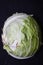 Vertical shot of a sliced in half cabbage isolated on a dark background