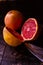 Vertical shot of sliced and whole fresh, juicy seasonal grapefruits and a knifeon a wooden table