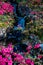 Vertical shot of a small cascading waterfall with pink floers