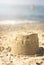 Vertical shot of a small sandcastle at beach under the sunlight with a blurry background