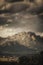 Vertical shot of a small town at the foot of a high rocky mountain under a cloudy sky