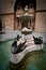 Vertical shot of a small water pool with a fountain and three black swans in front of a building