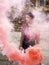 Vertical shot smoking bomb. Alternative girl punk holds pink smoke grenade in the hands. Football ultras in stadium