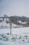 Vertical shot of a snow-covered fenced agricultural field with bare trees