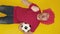 Vertical shot of soccer fan in red uniform cheering over yellow background