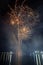 Vertical shot of a Spectacular night sky with an array of fireworks exploding over a body of water