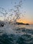 Vertical shot of splashing seawater with sunset sky in the background
