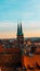 Vertical shot of St. Sebald church's two towers appearing in the cityscape of Nurnberg during sunset