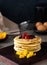 Vertical shot of a stack of fluffy pancakes with fresh fruits and honey on a wooden board