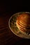 Vertical shot of a stack of freshly baked pancakes in a white plate on a wooden surface