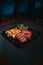 Vertical shot of steaks, baked potato, and a greeny leaf salad on a black plate