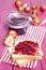 Vertical shot of strawberry jam spread on toasted bread on a decorative pink picnic table