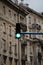 Vertical shot of a streetlight lighting green with buildings in the background at Rijeka Croatia