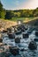 Vertical shot - strong water stream with stones and big rocks inside flowing from reservoir dam in the high mountain area on