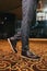 Vertical shot of a stylish man in textured gray suit pants and brown and black brogue shoes