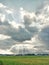 Vertical shot of the sun shining through a huge cloudscape over a green field