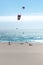 Vertical shot of the sunny Playa del Guincho with people parachuting in the sea, Portugal