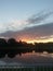 Vertical shot of a sunset on the cloudy sky  with silhouetted trees and lake from a balcony