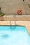 Vertical shot of a swimming pool with a step, and a lifesaver hung on the wall in the background