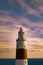 Vertical shot of a tall lighthouse with a pink cloudy sky background