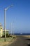 Vertical shot of the tall street lamps on the side of the road gleaming under the blue sky