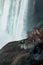 Vertical shot of tourists in raincoats admiring Niagara Falls from a close spot