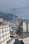 Vertical shot of tower cranes beside a building undergoing construction