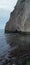 Vertical shot of a towering cliff face near the shoreline of a beach