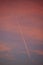 Vertical shot of the trail of the plane in the colorful sunset sky