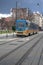 Vertical shot of a tram passing through narrow street with buildings in downtown, street scene