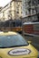 Vertical shot of a tram passing through narrow street with buildings in downtown, street scene