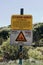 Vertical shot of two Danger Signs surrounded by green trees and bushes