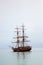 Vertical shot of two-masted wooden ship sailing in the sea under cloudy sky